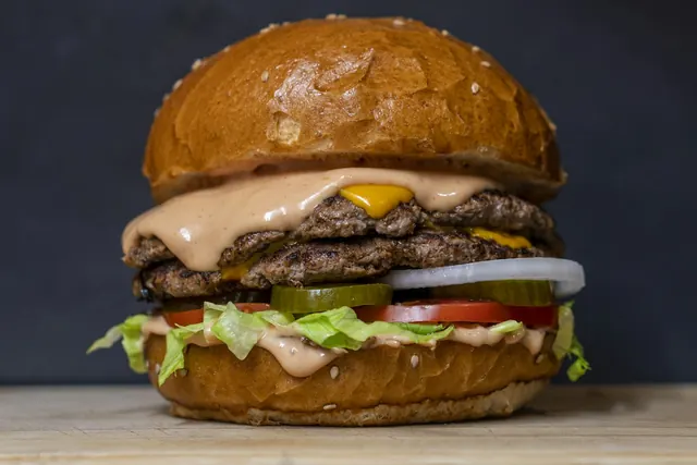 Double smash burger with cheese, lettuce and tomato on a dark background