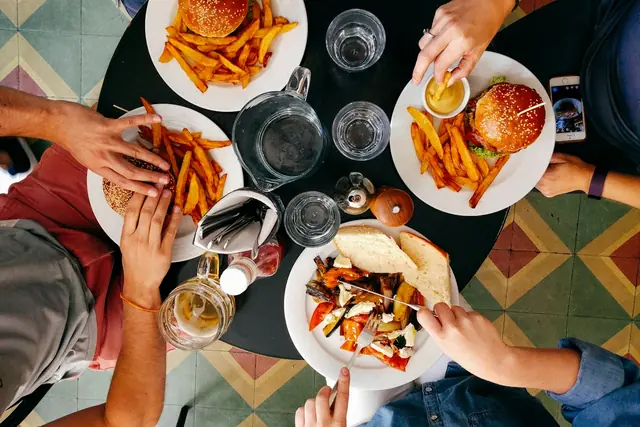 Friends sharing burgers, fries and salads around a table